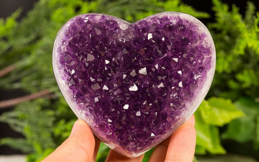 Purple Amethyst crystal held in a hand.