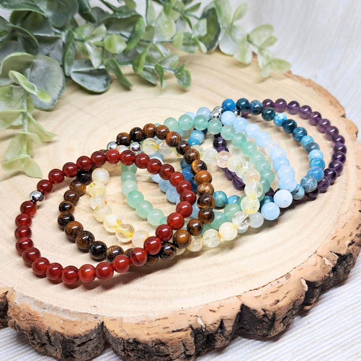 7 bead crystal bracelets on a wood surface.