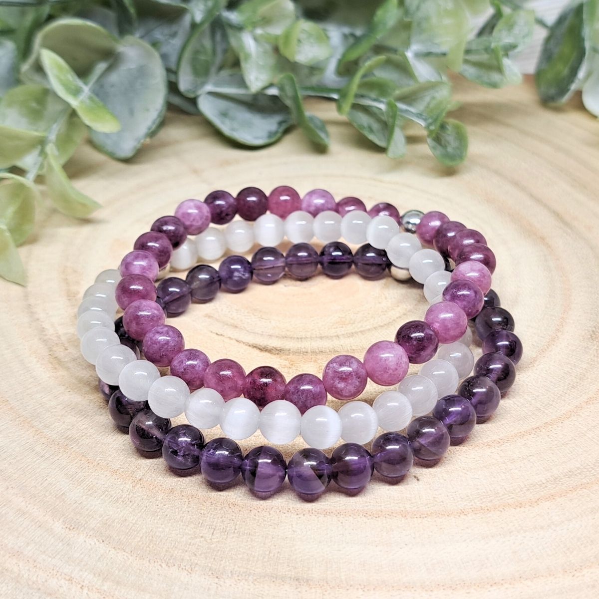 Purple and white crystal bead bracelets on a wood surface.