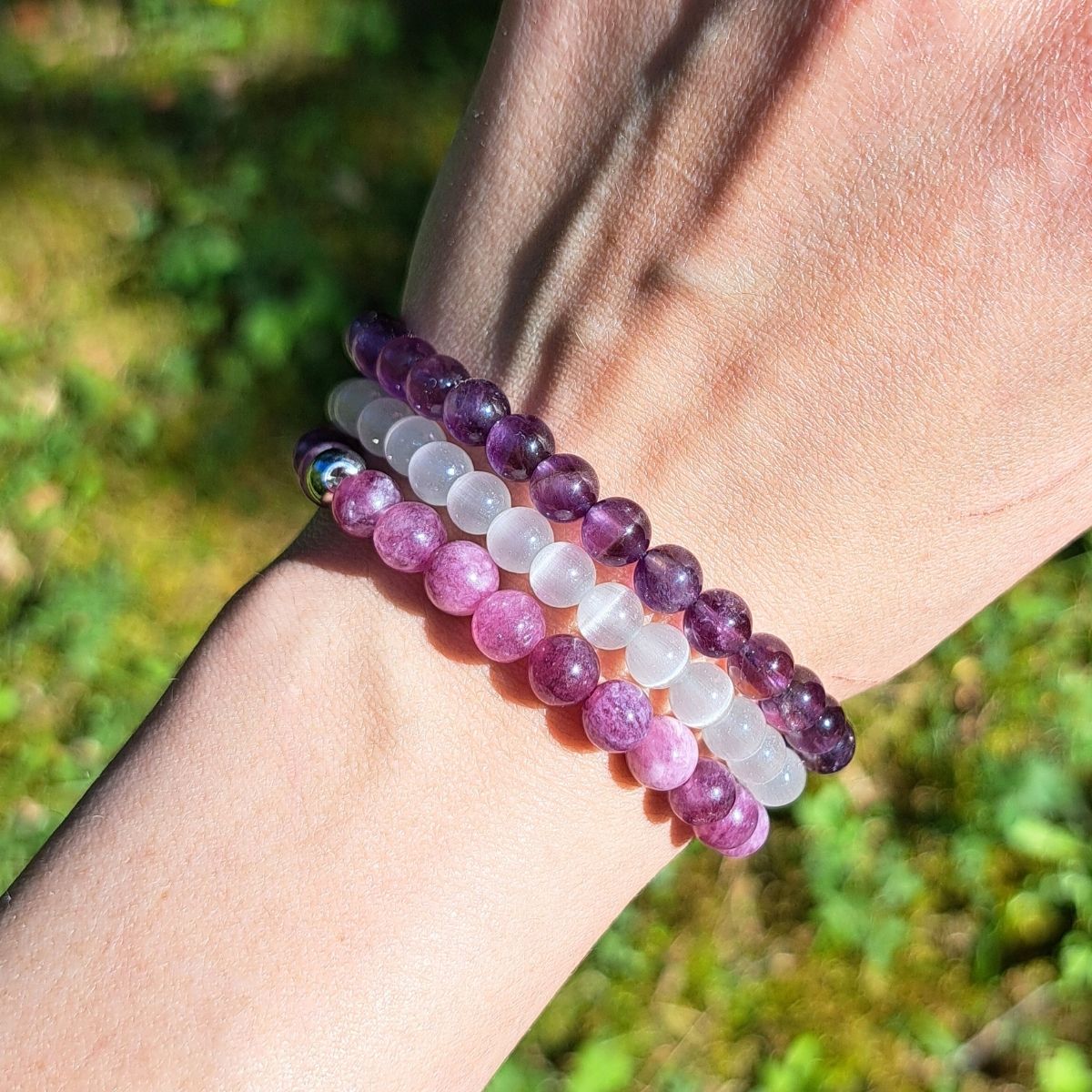 Three stone bead bracelets on a wrist.