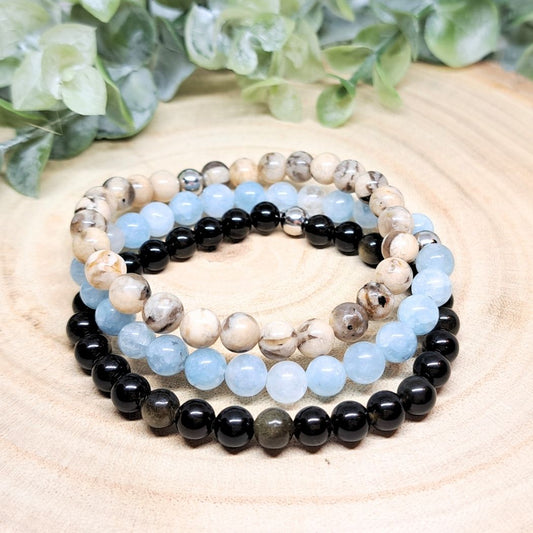 A set of 3 crystal bead bracelets on a wood surface.