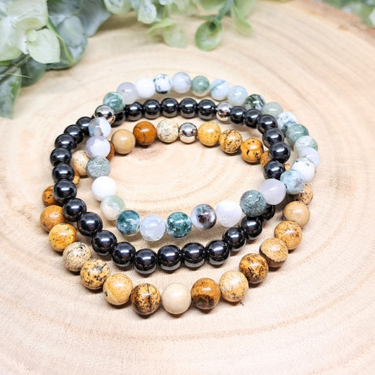 A set of 3 crystal bead bracelets on a wood surface.