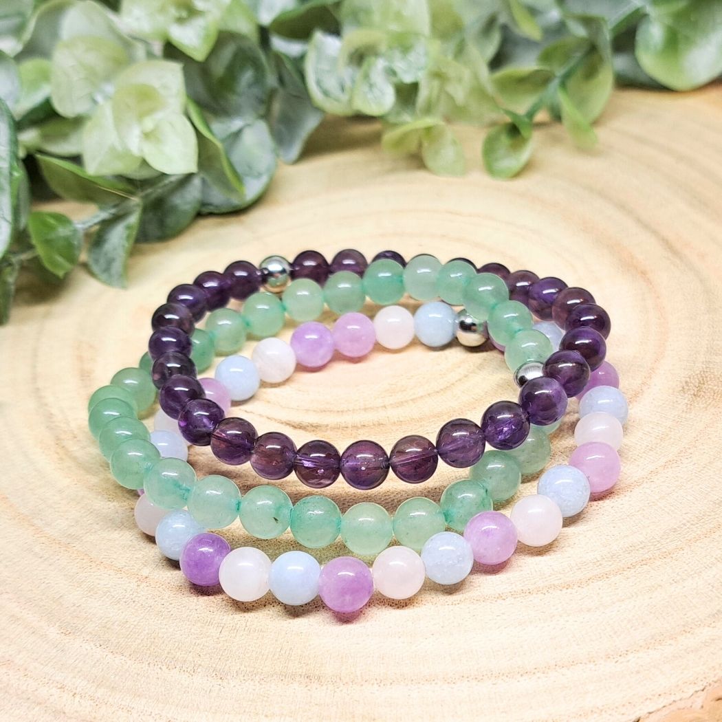 3 crystal bead bracelets on a wood surface.