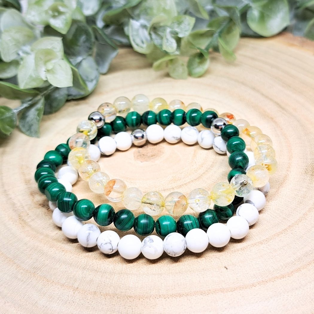 A set of 3 crystal bead bracelets on a wood surface.