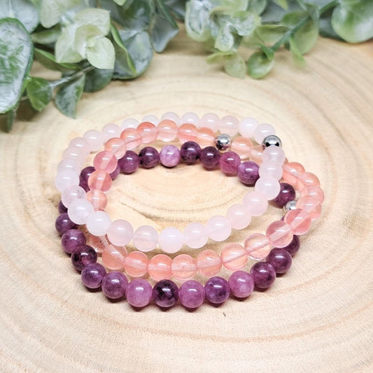 Rose quartz and Lepidolite bracelets on a wood surface.