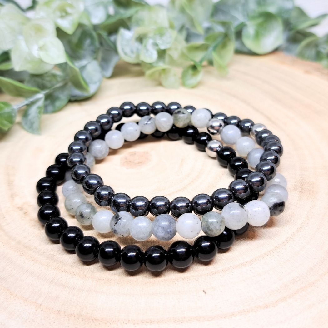 Black and gray bead bracelets on a wood surface. 