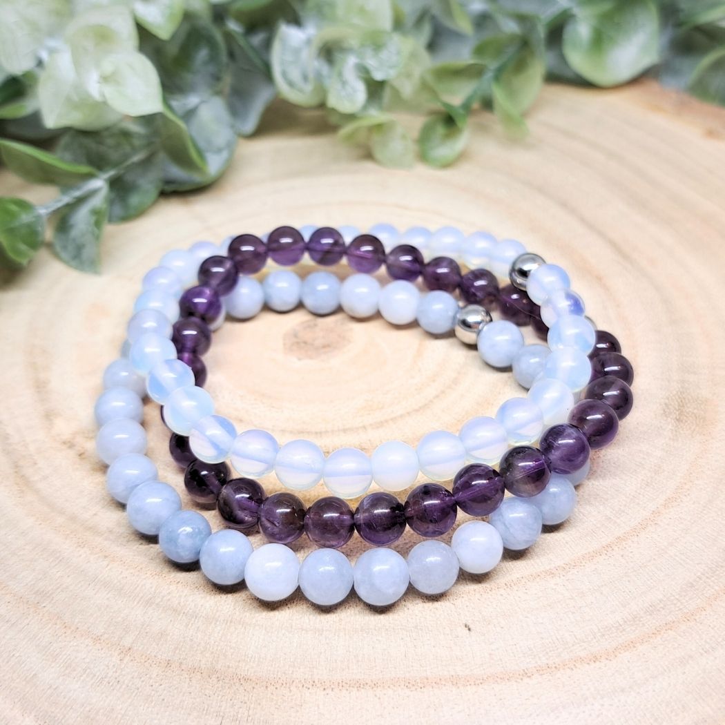 3 blue and purple crystal bead bracelets on a wood surface.