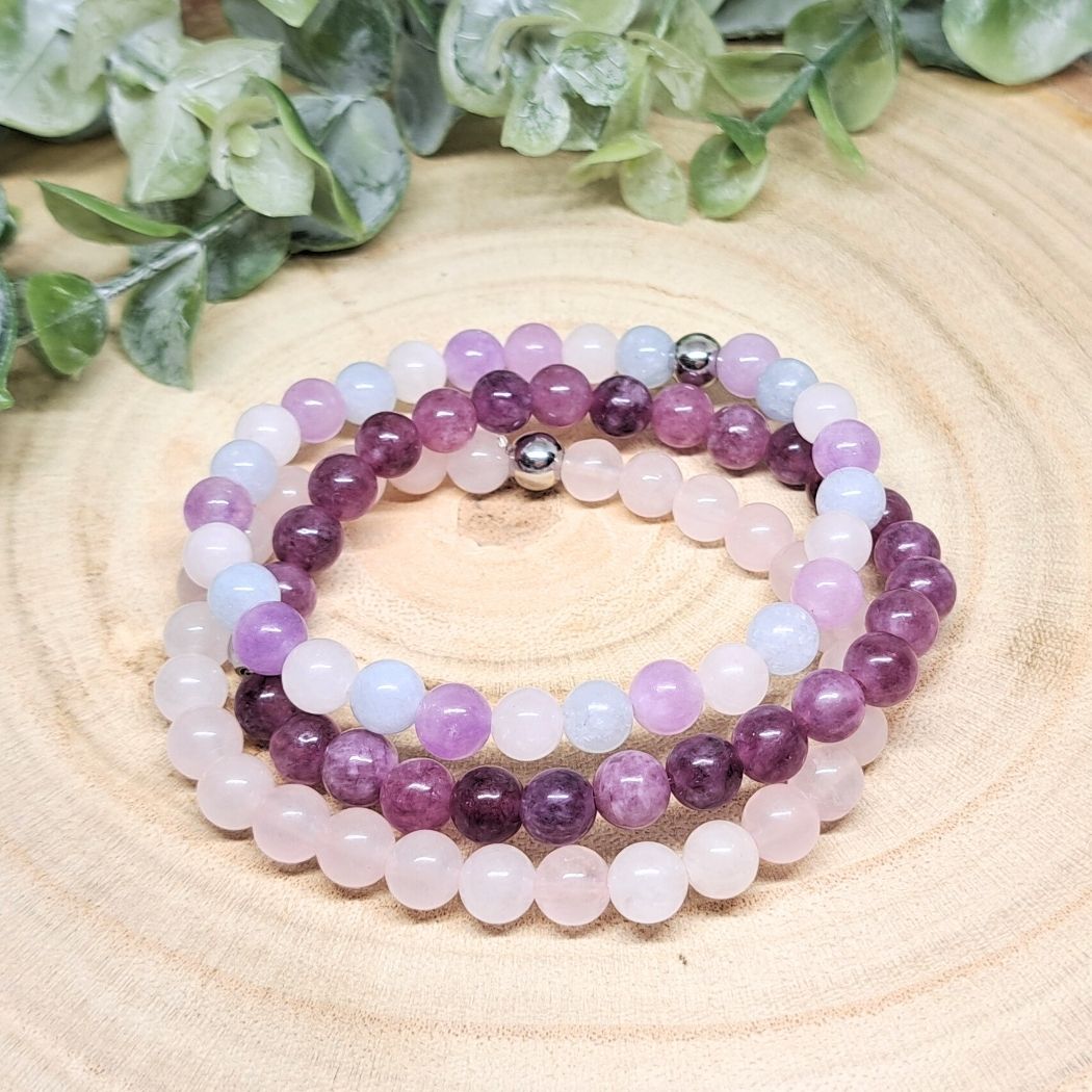 Purple and pink bead crystal bracelets on a wood surface.