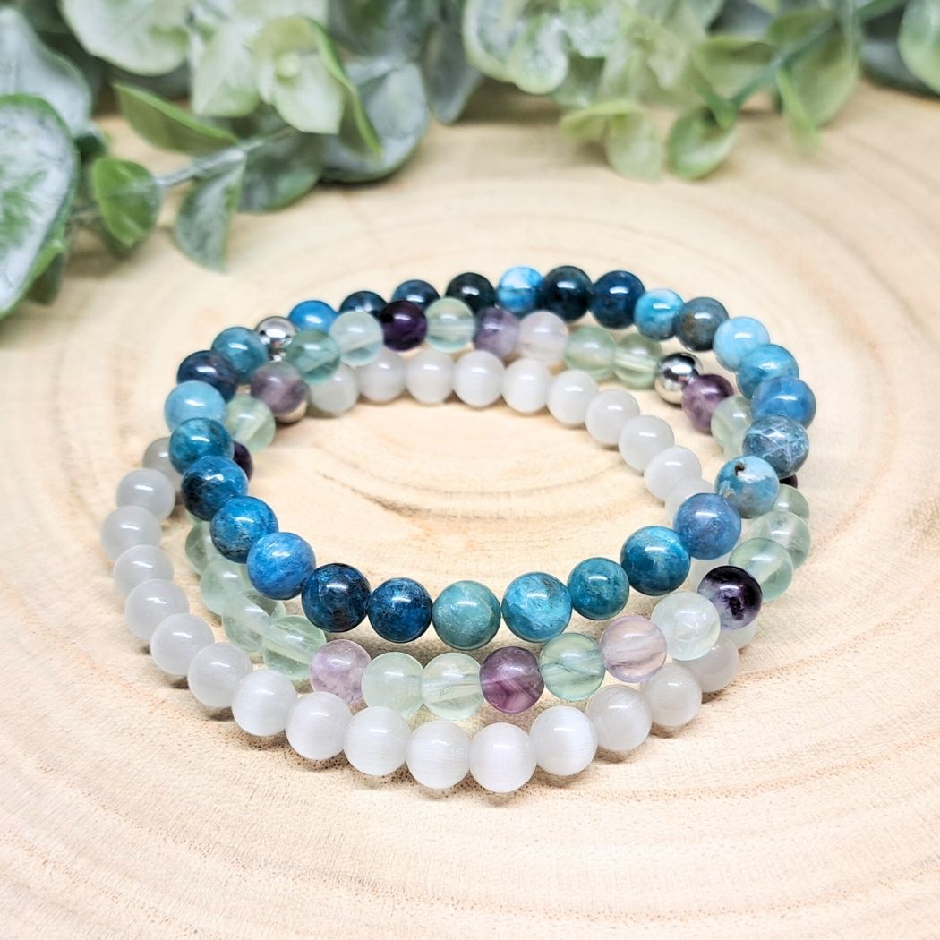 Stone bead bracelets on a wood surface.