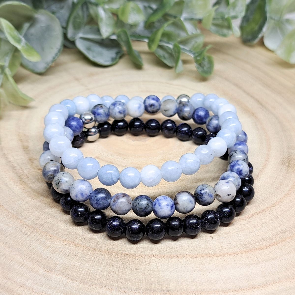 3 blue stone bracelets on a wood surface.