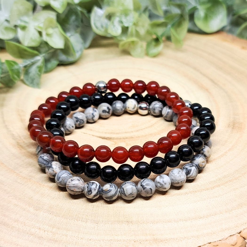 Red and black bead bracelets on a wood surface.